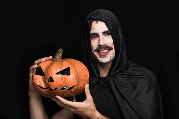 Homem jovem, em, traje halloween, posar, com, abóbora