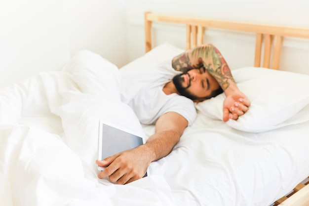Homem jovem, encontrar-se cama, com, tablete digital