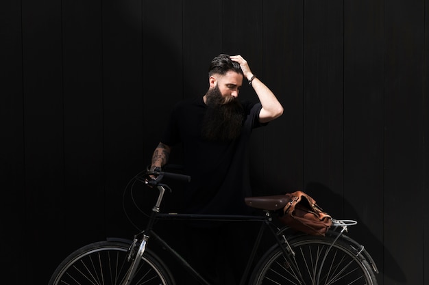 Foto grátis homem jovem, ficar, perto, bicicleta, com, seu, passe, cabeça, contra, experiência preta