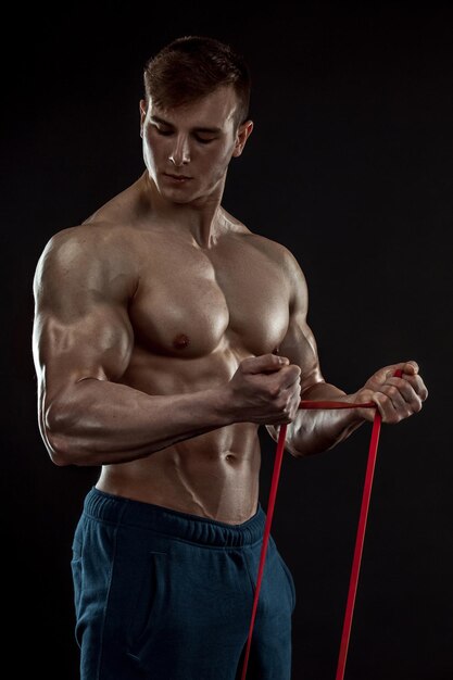 Homem jovem fisiculturista em fundo preto. Tronco masculino. alívio muscular