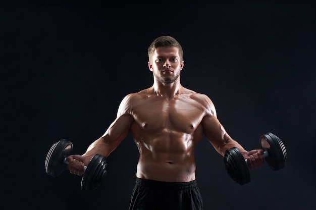 Foto grátis homem jovem musculoso, levantamento de pesos em fundo preto