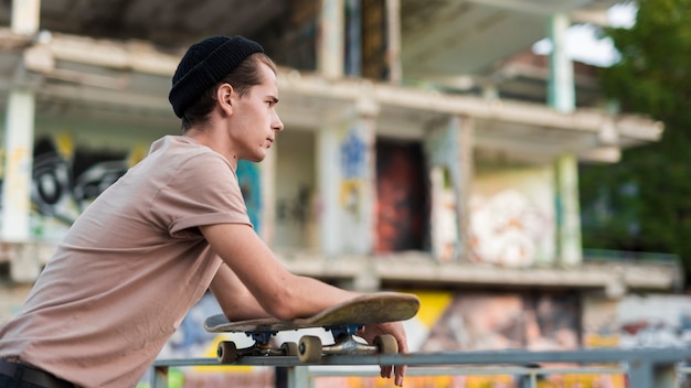 Foto grátis homem jovem, posar, com, skateboard