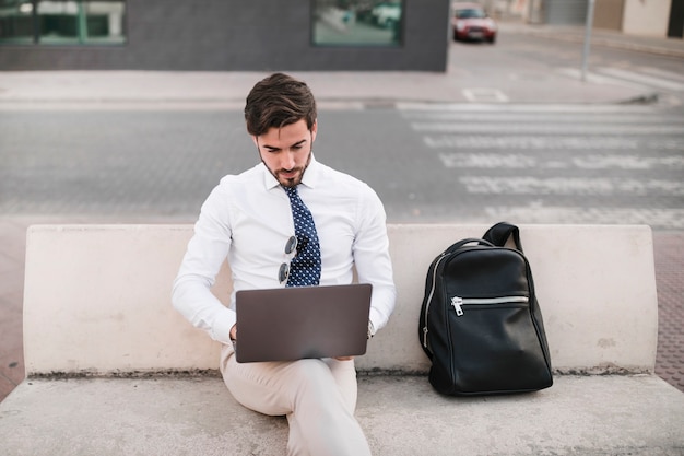 Foto grátis homem jovem, sentar-se banco, trabalhando, ligado, laptop