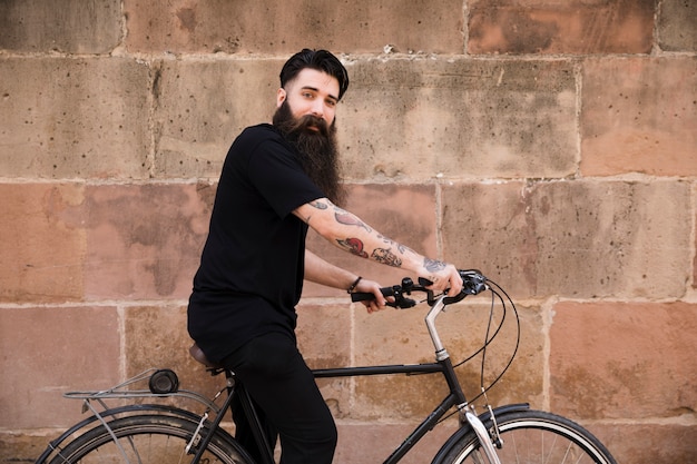 Homem jovem, sentar-se bicicleta, frente, parede resistida