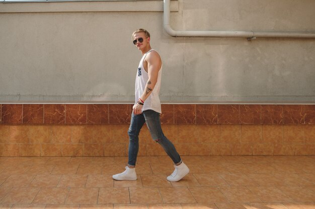 Homem jovem tatuado hipster com óculos de sol andando