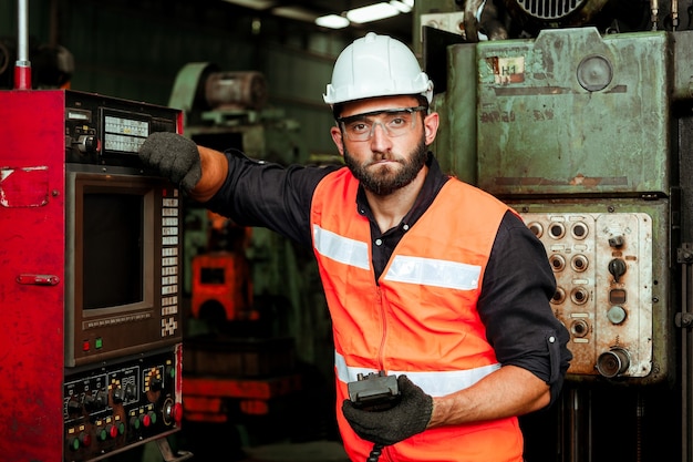 Homem jovem trabalhador industrial trabalhando com máquina de metal em fábrica com muitos equipamentos Foto Premium