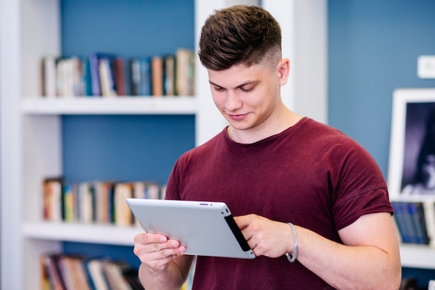 Foto grátis homem jovem, usando, tabuleta, em, biblioteca