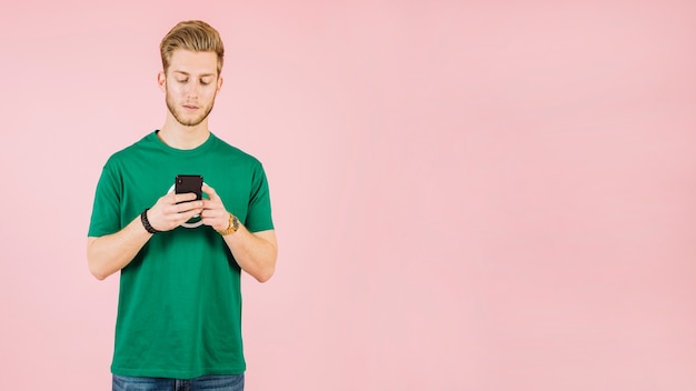 Homem jovem, usando, telefone móvel, ligado, cor-de-rosa, fundo