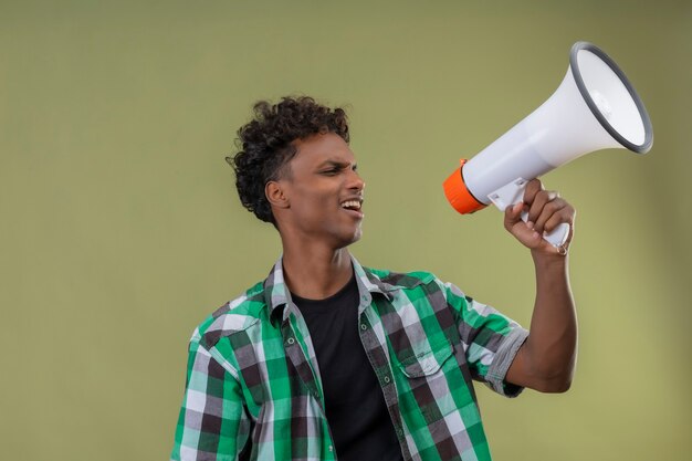Homem jovem viajante afro-americano gritando para o megafone
