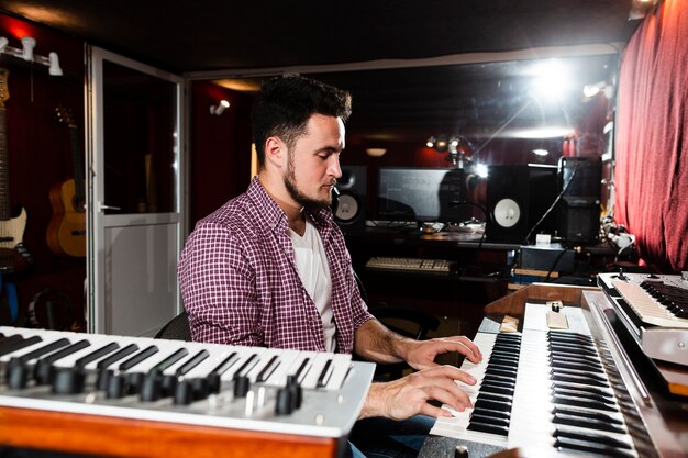 Homem lateral, tocando o teclado no estúdio