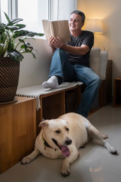 Homem lendo em casa com seu companheiro de cachorro