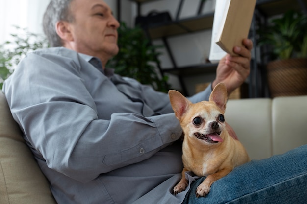 Homem lendo um livro em casa ao lado de seu cachorro