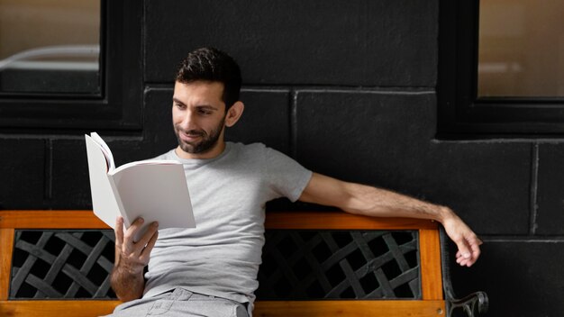 Homem lendo um livro interessante em um banco