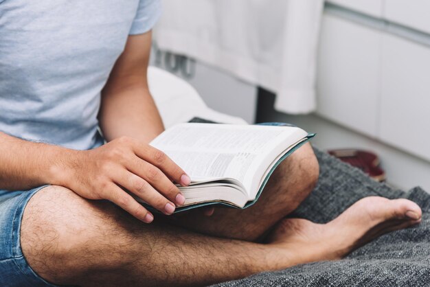 Homem lendo um livro na vida universitária do quarto