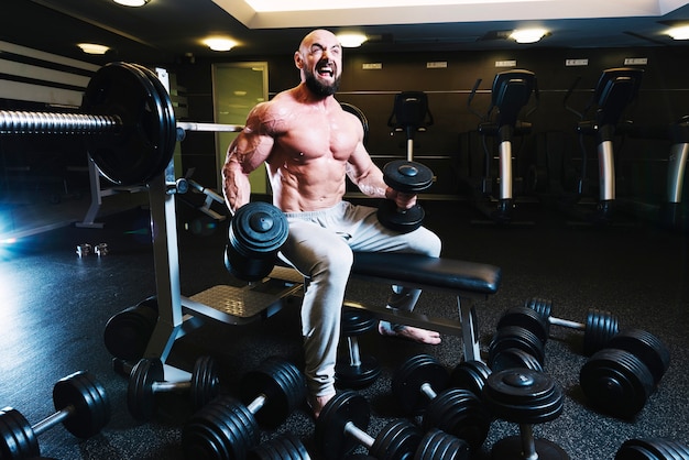 Foto grátis homem levantando dumbbells com rosto tenso