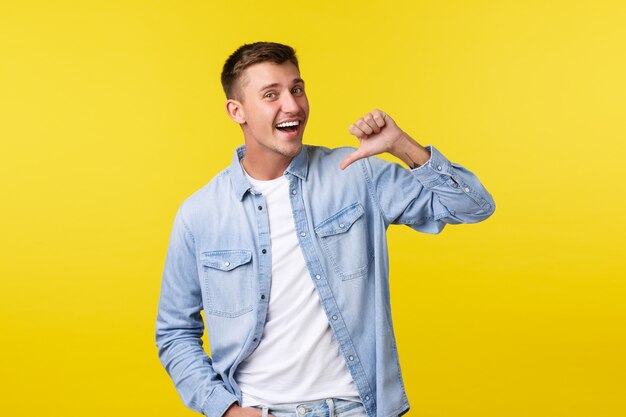 Homem loiro sorridente bonito entusiasta com sorriso feliz, apontando para si mesmo como voluntário, falando sobre realização pessoal e objetivo, quer participar, fundo amarelo.