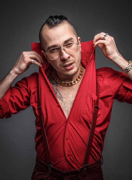 Foto grátis homem louco em óculos de camiseta vermelha e tatuagem nas mãos isoladas em cinza.