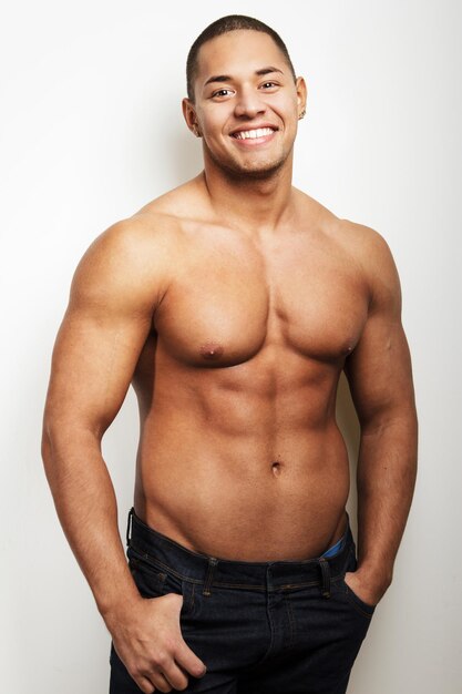 Homem macho sem camisa atraente mostrando seu corpo musculoso. Isolado no fundo branco