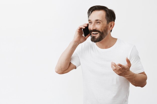 Homem maduro barbudo e despreocupado posando com seu telefone