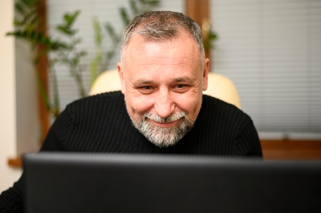 Homem maduro, olhando através de seu laptop