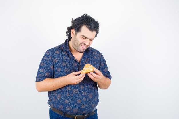Homem maduro, olhando para o produto de pastelaria na camisa e olhando feliz, vista frontal.