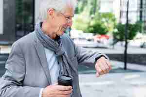 Foto grátis homem mais velho elegante na cidade olhando smartwatch