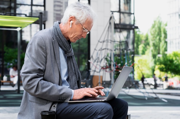 Homem mais velho elegante na cidade usando laptop