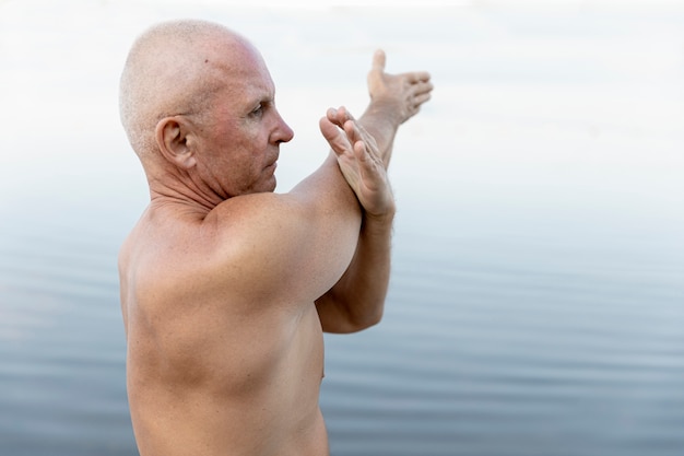 Homem mais velho, estendendo-se perto da água