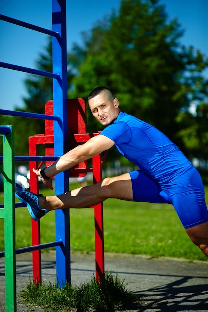 Homem masculino saudável saudável considerável do atleta do srtong que exercita no parque da cidade - conceitos da aptidão em um lindo dia de verão na barra horizontal