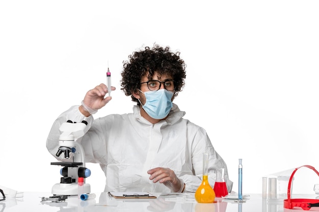 homem médico em traje de proteção e máscara segurando a injeção em branco