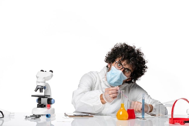 Foto grátis homem médico em traje de proteção e máscara trabalhando com soluções em branco