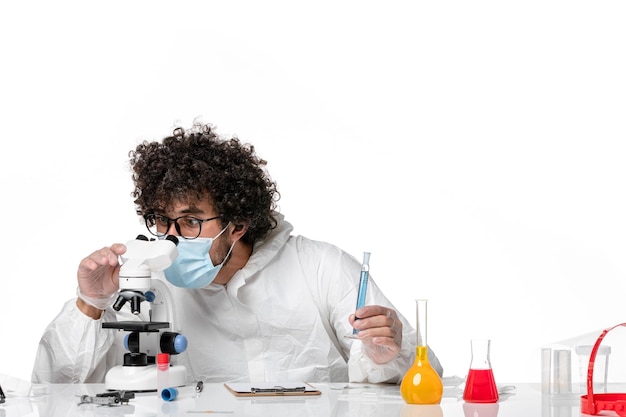 Foto grátis homem médico em traje de proteção e máscara usando microscópio em branco