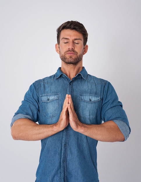 Homem meditando e vestindo uma camisa jeans