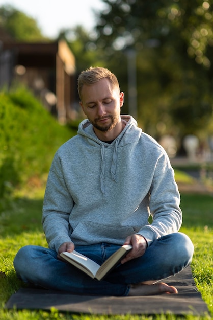 Foto grátis homem meditando no parque enquanto lê