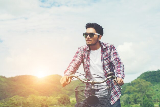 Homem moderno novo que monta a bicicleta para o topo da montanha desfrutar com