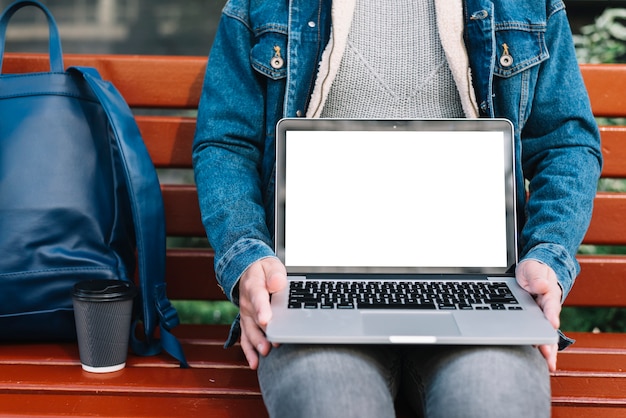 Homem moderno sentado no banco com modelo de laptop