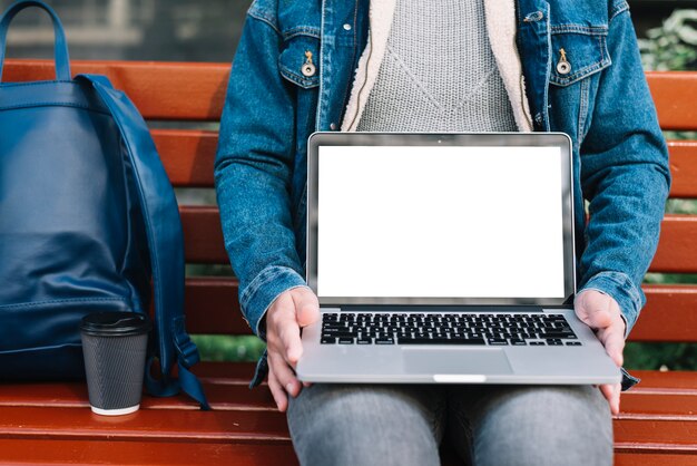 Homem moderno sentado no banco com modelo de laptop