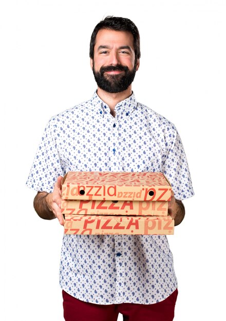 Homem moreno bonito com barba segurando uma pizza