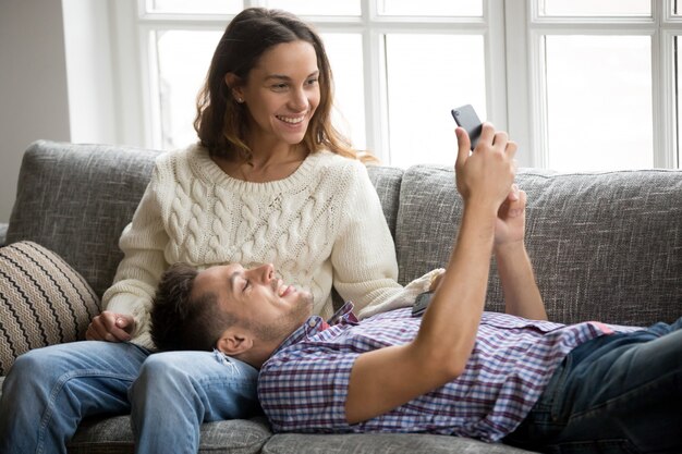 Homem, mostrando, mulher, novo, telefone móvel, app, relaxante, ligado, sofá