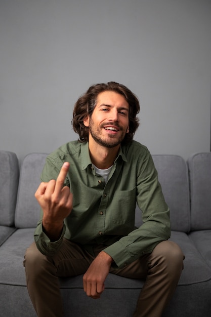 Foto grátis homem mostrando o dedo do meio enquanto está sentado no sofá