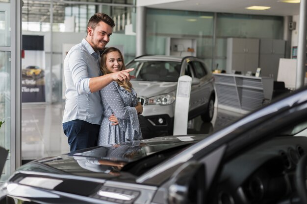 Homem mostrando para sua namorada um carro