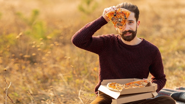 Foto grátis homem mostrando uma fatia de pizza com espaço de cópia