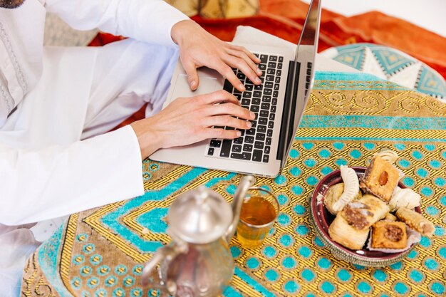 Foto grátis homem muçulmano com comida e laptop