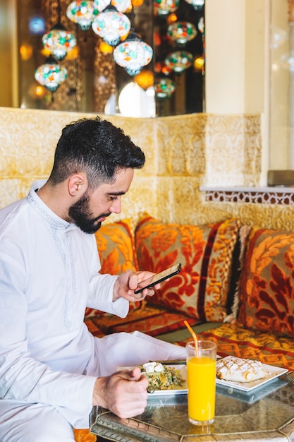 Foto grátis homem muçulmano olhando para smartphone