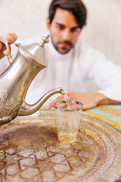 Homem muçulmano sentado na mesa com chá