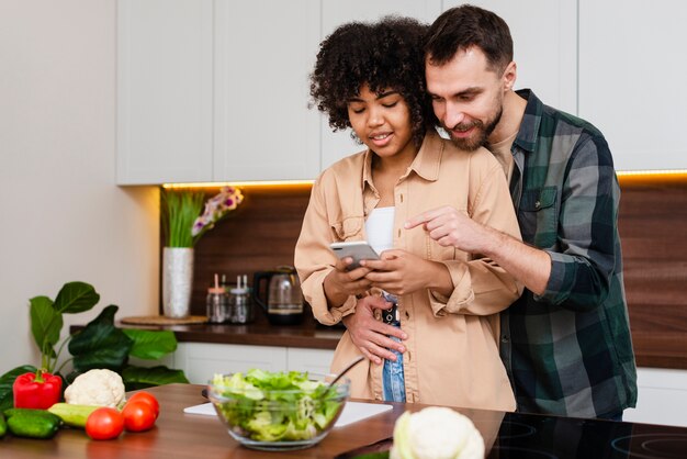 Homem mulher, olhando telefone, cozinha