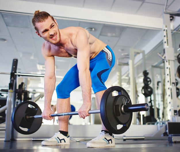 Homem muscular que faz o exercício pesado