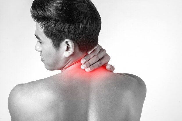 Homem muscular usa alças no pescoço para aliviar a dor isolada no fundo branco.