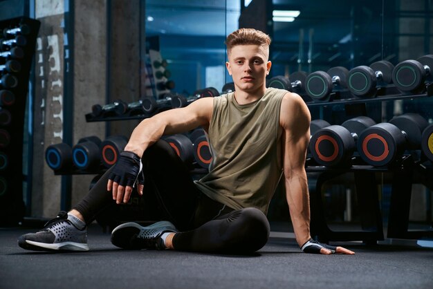 Homem musculoso posando no chão no ginásio