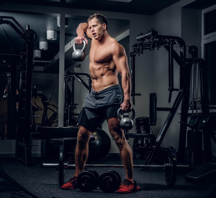 Foto grátis homem musculoso sem camisa em uma academia fazendo exercícios de ombros com halteres.
